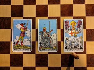 A three-card tarot spread. The Page of Swords, the Queen of Swords, and Judgement.