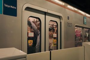 Tokyo Metro riders behind the closed door of a passenger train car.