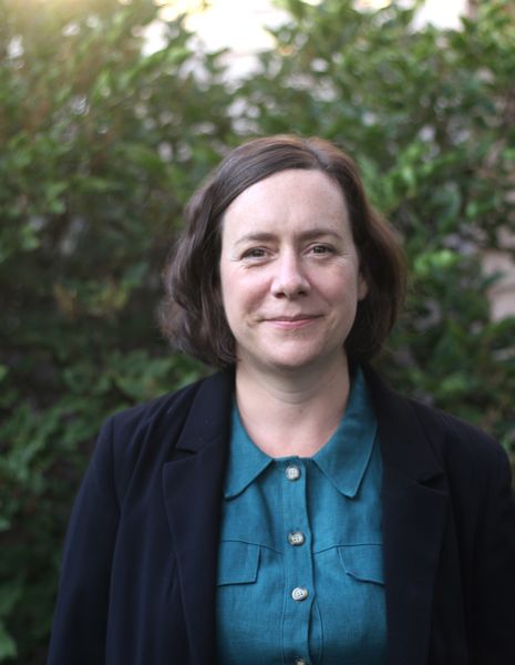 Amanda White (Photo by Brad Isaacs), illustrator of Shy Cat and the Stuff-the-Bus Challenge. A person with short brown hair wearing a teal button-up shirt and a dark blazer, standing outdoors in front of green foliage and smiling softly at the camera. Amanda White (Photo by Brad Isaacs), illustrator of Shy Cat and the Stuff-the-Bus Challenge. A person with short brown hair wearing a teal button-up shirt and a dark blazer, standing outdoors in front of green foliage and smiling softly at the camera.