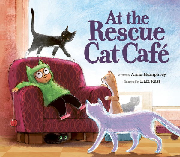 Illustrated book cover of At the Rescue Cat Café by Anna Humphrey, illustrated by Kari Rust. A child wearing a green cat-eared hoodie lounges on a red armchair while looking up at a black cat walking along the chair's backrest. Three more cats—a cream tabby with white paws, a purple-toned cat, and a hidden black cat with glowing eyes under the chair—surround the scene. The background shows a softly lit room with a large window and a framed picture of a cat.