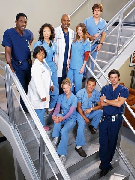 Photo of the cast of Grey's Anatomy in scrubs on a staircase. Image credit via Wikipedia