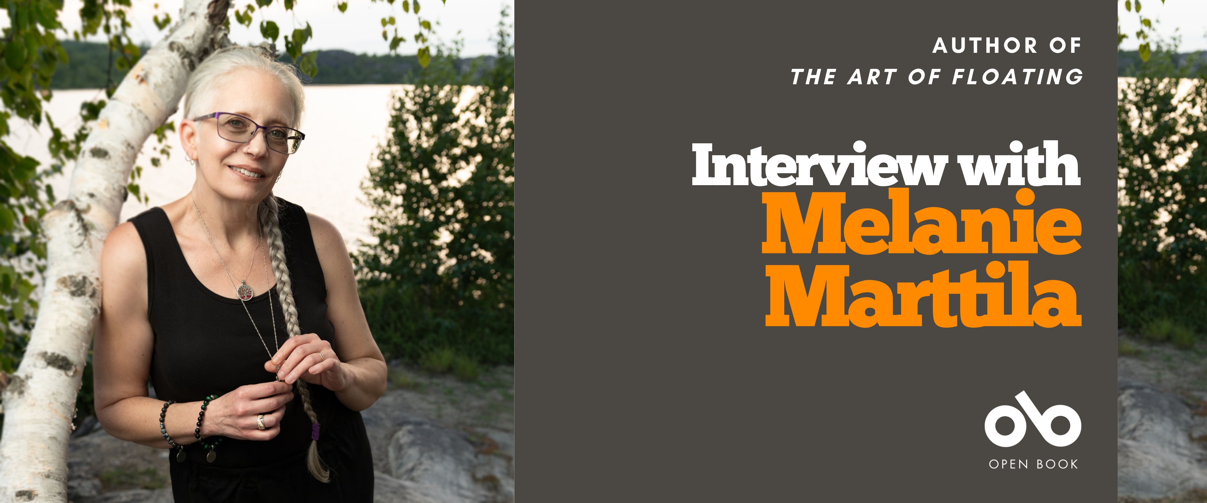 Interview with Melanie Marttila banner. Background image of the author, woman in black dress with grey hair and leaning on a birch tree near to baywater. Grey section to the right with text overlaid and the Open Book logo.