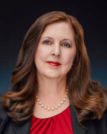 Professional headshot of Rosanna Micelotta Battigelli against a dark background. She has long, wavy brown hair with highlights, and wears a vibrant red top with a pearl necklace. She is smiling warmly at the camera with red lipstick, presenting a polished and approachable appearance. Professional headshot of Rosanna Micelotta Battigelli against a dark background. She has long, wavy brown hair with highlights, and wears a vibrant red top with a pearl necklace. She is smiling warmly at the camera with red lipstick, presenting a polished and approachable appearance.