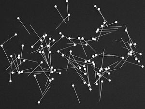 Sewing pins scattered on a black surface.