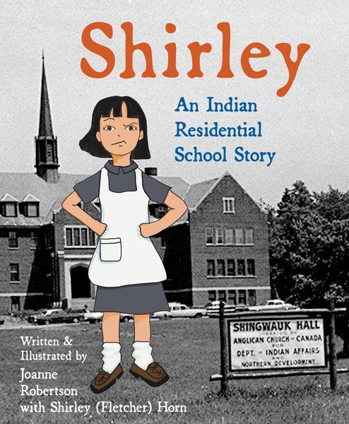 Shirley: An Indian Residential School Story by Joanne Robertson with Shirley (Fletcher) Horn. The cover features an illustrated young girl with short dark hair, wearing a gray dress, white apron, and brown shoes, standing with her hands on her hips. Behind her is a black-and-white photograph of a large brick building with a church steeple and a sign reading “Shingwauk Hall Anglican Church – Canada Dept. of Indian Affairs Northern Development.” The title “Shirley” is written in large orange letters at the top.