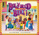 Book cover for Bollywood Beat! written by Anita Yasuda and illustrated by Devika Oza. The title appears in large, dimensional purple letters with decorative patterns and star accents, positioned at the top center. Below, a diverse group of children and adults dance together on a neighborhood street, their poses dynamic and celebratory. The characters wear vibrant clothing in shades of blue, yellow, green, and pink, many featuring traditional South Asian patterns and silhouettes. The background depicts a colorful residential street with pink, yellow, and teal building facades, windows, and doorways. The entire composition is framed by a decorative border with repeating geometric and floral motifs in warm tones—orange, yellow, and red—evoking traditional South Asian textile and architectural design. The overall palette is bright and saturated, with a playful, energetic tone that mirrors the movement and joy of Bollywood dance. Illustration style is warm and approachable, with rounded forms and expressive character work.