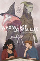 Cover of Who We Are in Real Life by Victoria Koops. A teenage boy and girl sit over a gaming board on a table in the foreground, the boy with red hair and a playful look on his face. The girl with olive skin and brown hair and glasses, appearing more shy and apprehensive. The larger figures of a wizard an elf are above them in the background.