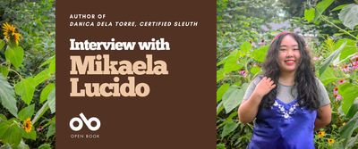 interview with Mikaela Lucido, author of Danica dela Torre, Certified Sleuth banner. Background image of dense woodland greenery with author to right of banner standing in forefront, young woman with long black hair, wearing a blue dress and smiling outwardly. Solid burgundy area to centre left with text and Open Book logo overlaid.