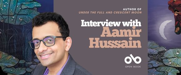 Book banner featuring a smiling man with glasses, identified as Aamir Hussain. The text reads: "Interview with Aamir Hussain, author of Under the Full and Crescent Moon." The background includes artistic illustrations of lily pads, a crescent moon, and the Open Book logo.
