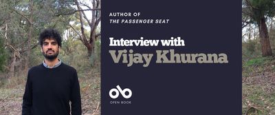 Interview with Vijay Khurana, author of The Passenger Seat banner. Background image of woodland with fallen leaves and brush and a slight slope of ground rising up toward stands of trees. Image of author to left of banner, and with thick, curly, hair hair and an impressive beard. Standing squarely with arms at sides and wearing a collared shirt under a black sweater. Solid dark blue section to centre right with text and Open Book logo overlaid.