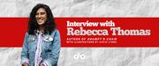 Interview with Rebecca Thomas, author of GRAMPY'S CHAIR, illustrated by Coco Lynge banner. Background image of crinkled white paper with wide red bar running horizontally across image, with text and Open Book logo overlaid in right half of image. Photo of author to the left of banner, young women with long, curly black hair falling down across the shoulders of her jean jacket, adorned with pins, wearing trendy glasses and a blue-striped over white collared shirt, smiling outwardly