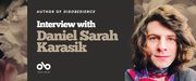 Interview with Daniel Sarah Karasik banner. Background image of pink flowers enlarged from cover and author photo to right of image, author with long brown hair smiling outwardly. To centre-left a solid burgundy area with text and Open Book logo overlaid.