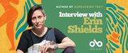 A promotional banner featuring playwright Erin Shields. She sits facing the camera, wearing a black shirt with abstract patterns and a silver cuff bracelet, against a vibrant background of abstract orange, yellow, and blue shapes. On the right side of the image, white and green text reads: "Author of Ransacking Troy — Interview with Erin Shields." The Open Book logo appears at the bottom with the text "Open Book" below it. The background includes stylized silhouettes and organic wave-like patterns.