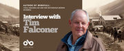 Interview with Tim Falconer, author of Windfall banner. Background image of old timey mining operation in northern town, with rolling, tree-covered hills in distance and many men milling about a hardscrabble mining camp in foreground. Solid burgundy section to centre-left with text and Open Book logo overlaid. Photo of author to centre-right, man with grey-white hair wearing a rugged jacket over a blue-plaid shirt, looking pleasantly outward.