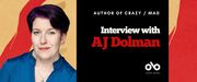 Interview with AJ Dolman banner. Image of author photo the left, person with purple shirt and short, dark hair, arms crossed and looking outward. To centre right a dark section with text overlaid and Open Book logo. Background is red and yellow pattern from book cover. 