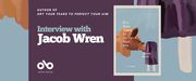 Interview with Jacob Wren, author of Dry Your Tears to Perfect Your Aim banner. Background image of pastel, light blue-grey colour with abstract brown shape to left, and abstract painted image of a purple popsicle to the right, from cover of book. Dark purple section to centre-left of banner with text and Open Book logo overlaid, and image of book cover featured to centre-right.