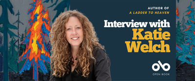Banner for an Open Book interview with author Katie Welch. On the left, a vivid painting of a burning tree in orange, yellow, and blue stands among dark green forest trees. On the right, a smiling portrait of Katie Welch with long curly light brown hair, wearing a black top, is set against a deep blue background. Text reads: “Author of A Ladder to Heaven — Interview with Katie Welch.” The Open Book logo appears at the bottom.