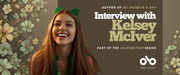 Smiling young woman wearing green shamrock accessories against a background of clovers. Text on the banner reads: “Author of St. Patrick’s Day — Interview with Kelsey McIver — Part of the Celebration Series.” Open Book logo appears at the bottom right.
