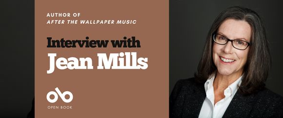 Interview with Jean Mills, author of After the Wallpaper Music banner. Background image author to right of banner. woman will long black hair and glasses, with a white blouse and suit jacket overtop, leaning slight and smiling against a dark textured backdrop. Solid green area to centre-left with text and Open Book logo overlaid.