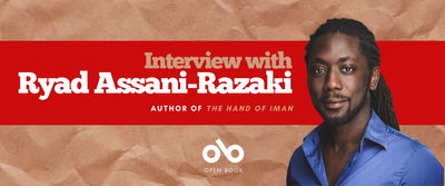 Banner featuring the title “Interview with Ryad Assani-Razaki” in bold white and beige text on a red background. Below, in smaller text, it reads “Author of The Hand of Iman.” On the right side is a portrait of Ryad Assani-Razaki wearing a blue shirt, set against a brown paper-textured background. At the bottom center is the Open Book logo.