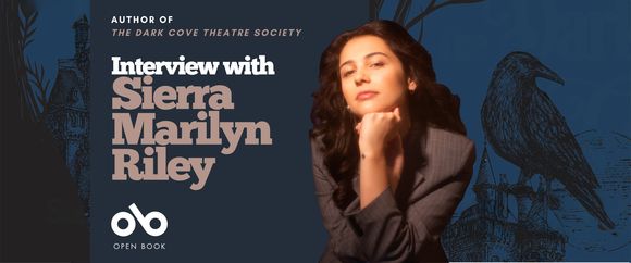 Promotional banner featuring author Sierra Marilyn Riley. She is seated with her chin resting on her hand, wearing a gray blazer and looking confidently at the camera. The background is dark blue with illustrations of a crow and gothic architecture. Text reads: “Author of The Dark Cove Theatre Society — Interview with Sierra Marilyn Riley.” The Open Book logo appears at the bottom left.