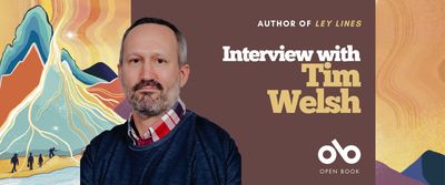 Interview with Tim Welsh, author of Ley Lines banner. Background image from cover of illustrated vibrantly coloured landscape with silhouettes of small miners and adventurers walking across dunes at the base of a mountain, with yellow and orange sky, all textured throughout. Solid plum section to centre with text and Open Book logo overlaid. Author photo to centre-left, man in dark blue knit-sweater over a plaid, collared shirt, with greying hair and neat beard, looking outwardly with authorial intensity.